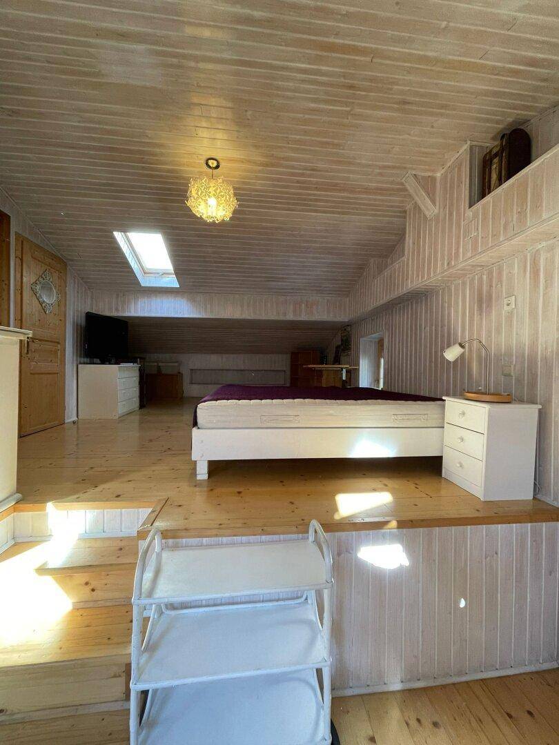 Offener Wohnbereich mit Schlafbereich auf einer erhöhten Plattform, Holzwänden und Dachfenstern.