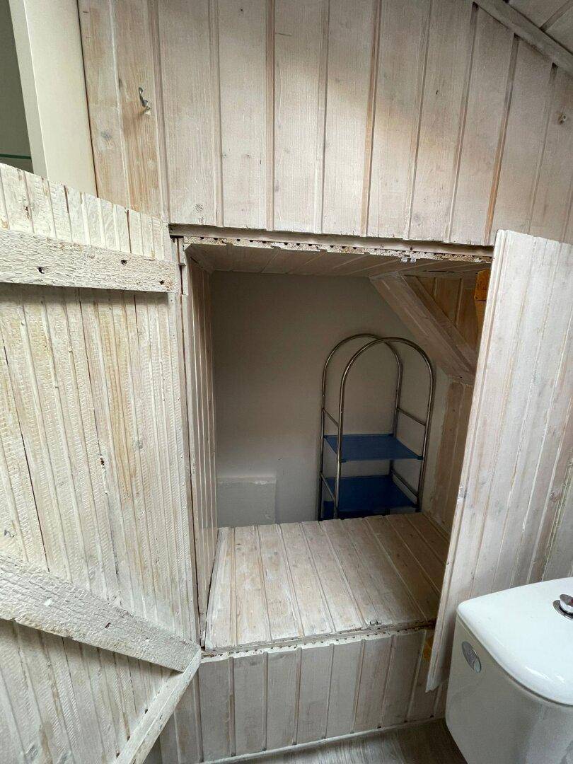 Praktischer Stauraum unter der Dachschräge, zugänglich durch rustikale Holztüren.
