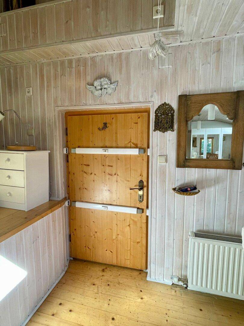 Rustikale Holztür mit Spiegel und Holzwänden in einem Übergangsbereich des Hauses.