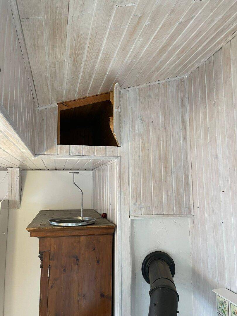 Detailansicht einer Holzwand und Decke mit einer kleinen Nische unter der Dachschräge.