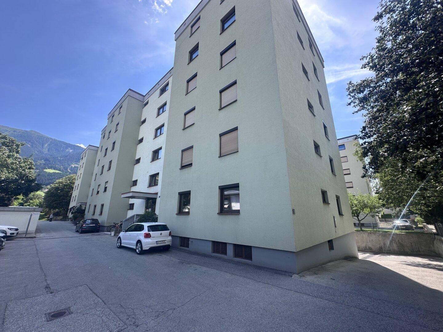 Mehrstöckiges Wohngebäude mit grüner Fassade und vielen Fenstern.