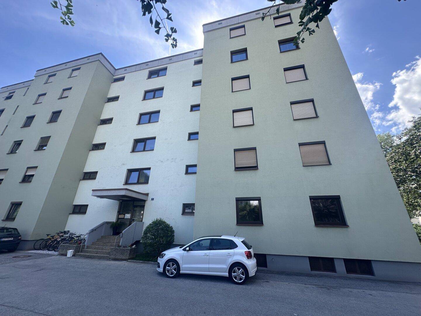 Ansicht eines hohen Wohngebäudes mit hellgrüner Fassade und vielen Fenstern.