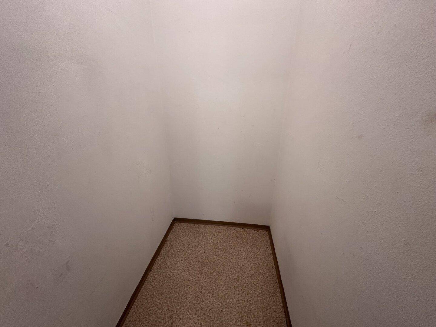 Kleiner Abstellraum mit Teppichboden und weißen Wänden.