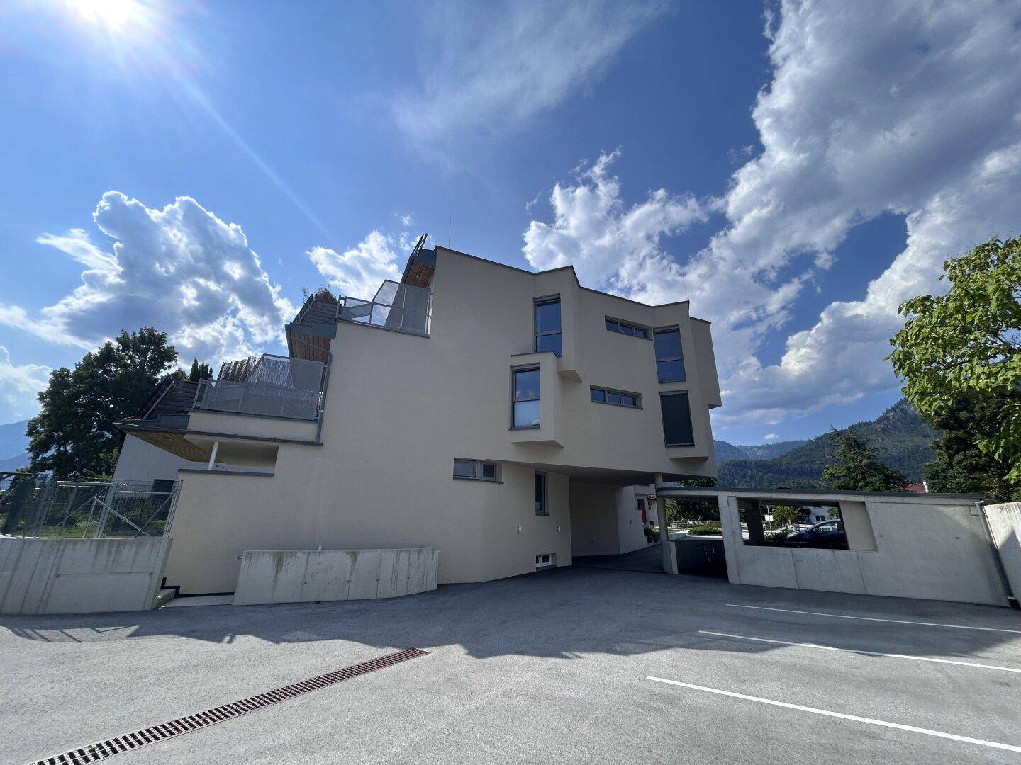 Moderne Architektur des Gebäudes mit mehreren Terrassen und einem beeindruckenden Bergpanorama.