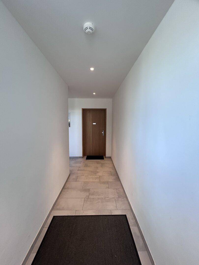 Freundlicher Hausflur mit Fliesenboden und einer modernen Holztür zum Apartment.