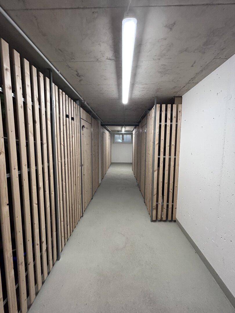 Kellerabteil mit Holzlattenwänden für individuelle Lagermöglichkeiten und Betonboden.