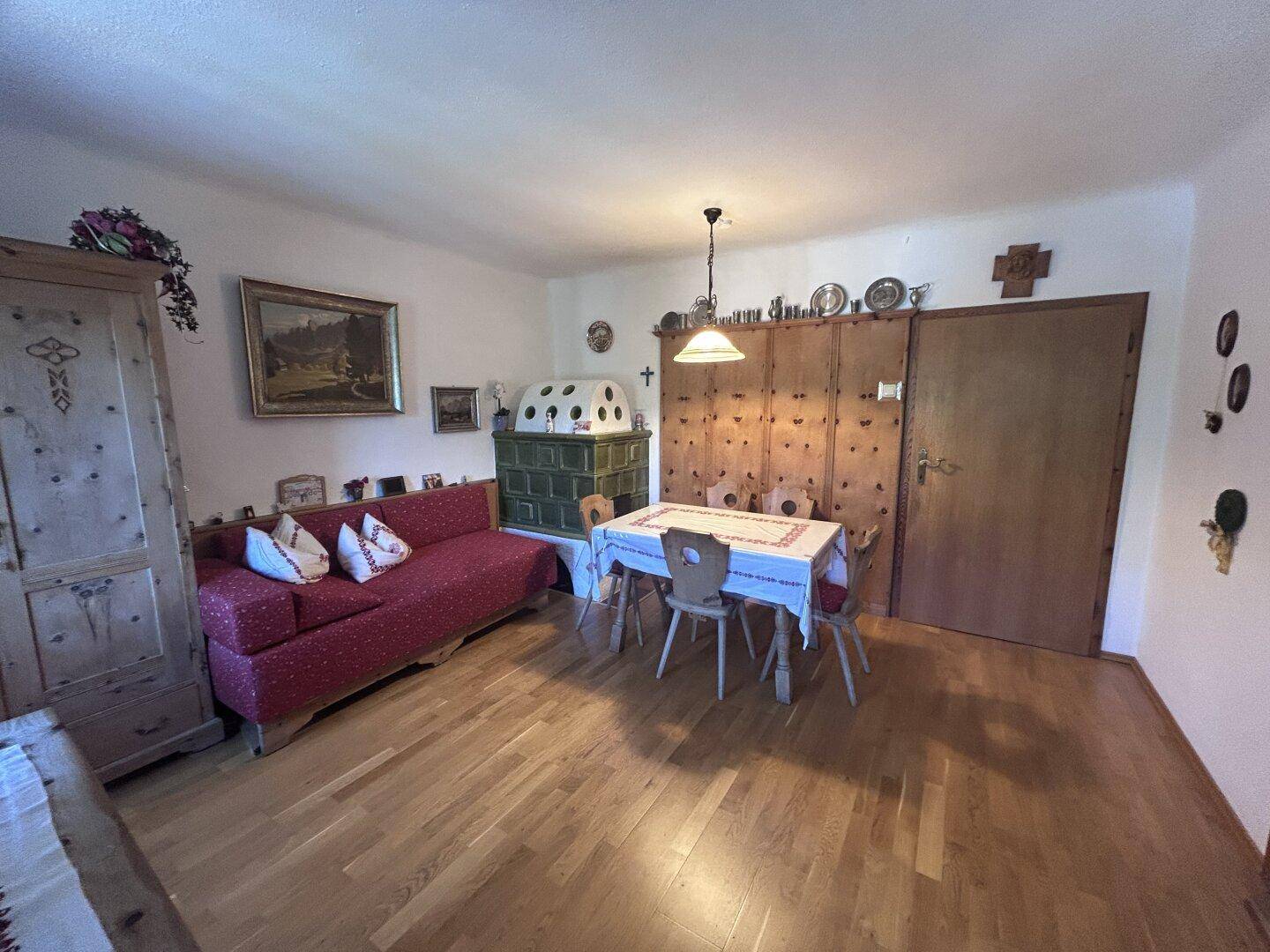 Gemütlicher Wohn-Essbereich im alpinen Stil mit traditionellen Holzmöbeln und einem Kachelofen.
