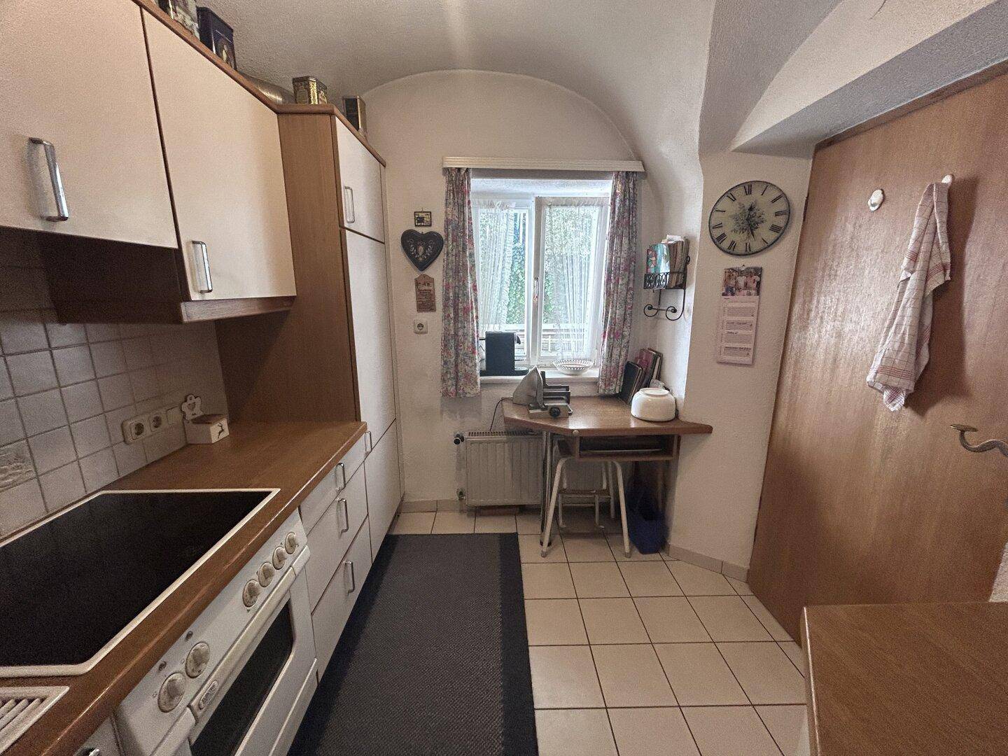 Funktionale Küche mit Fenster, Arbeitsbereich und Fliesenboden, ideal für den täglichen Gebrauch.
