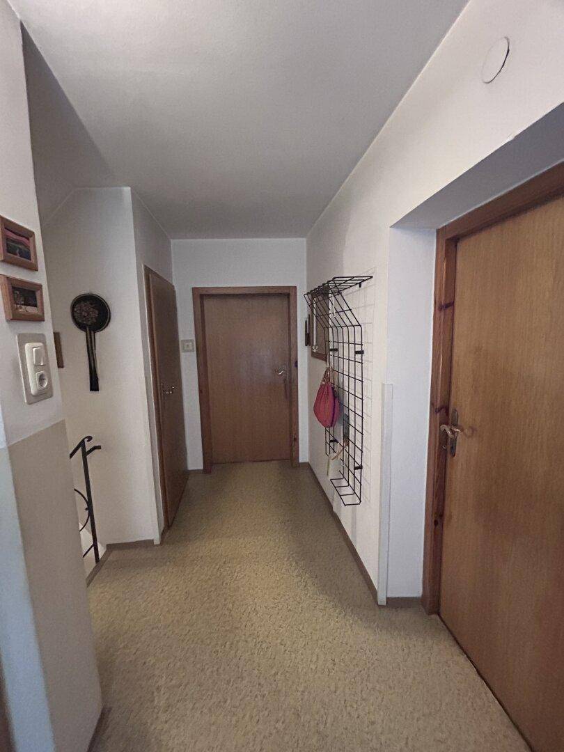 Flur mit Teppichboden, mehreren Holztüren und einer Garderobe an der Wand.