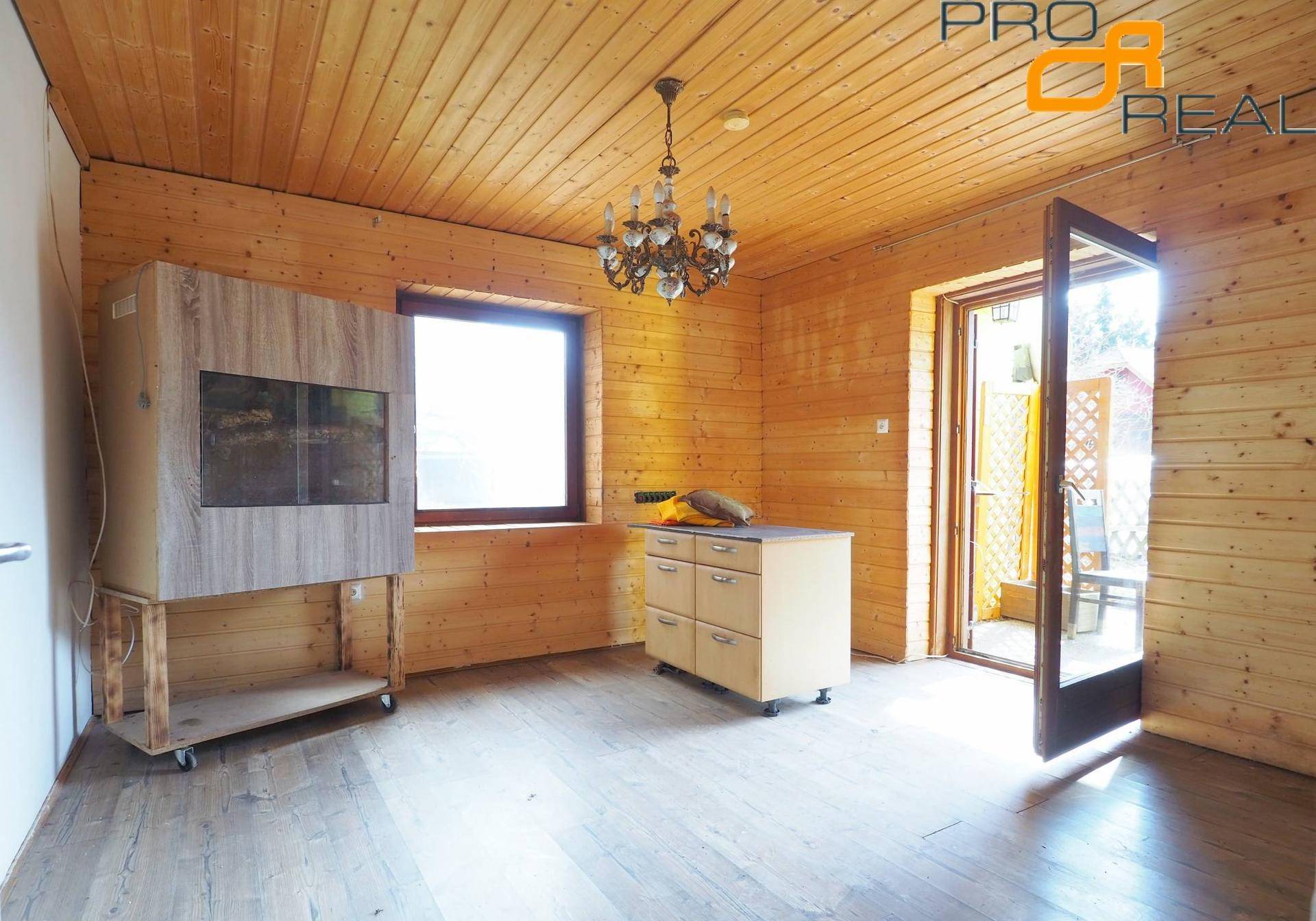 Rustikaler Raum mit Holzvertäfelung an Wänden und Decke, Holzboden und Kronleuchter.