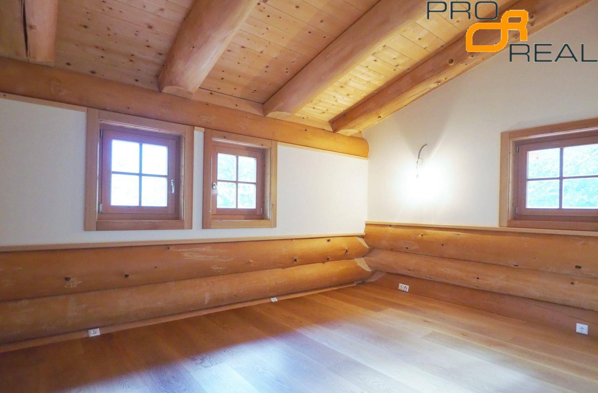 Helles Schlafzimmer mit Holzboden, Holzwänden und Dachschräge.