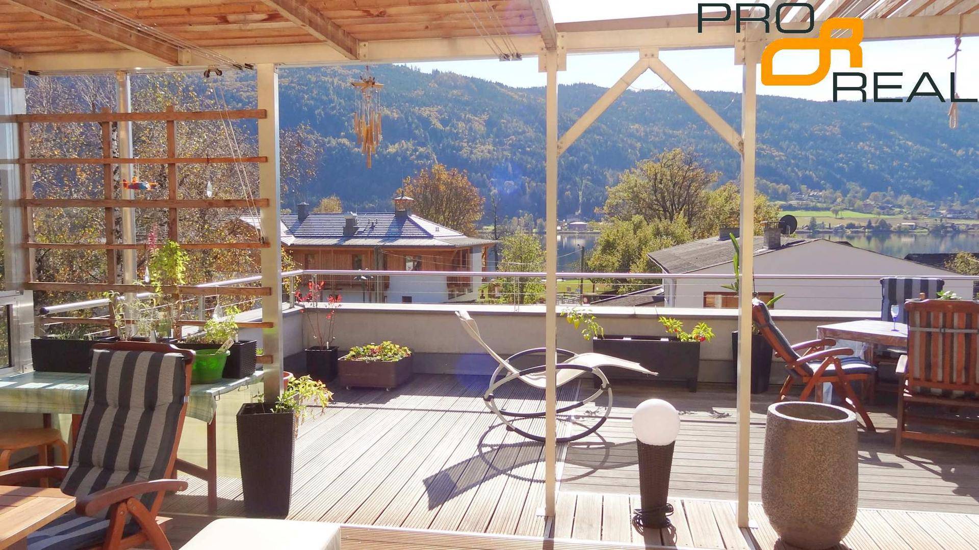 Großzügige Dachterrasse mit Holzdeck, Pergola und Sitzgelegenheiten mit Seeblick.