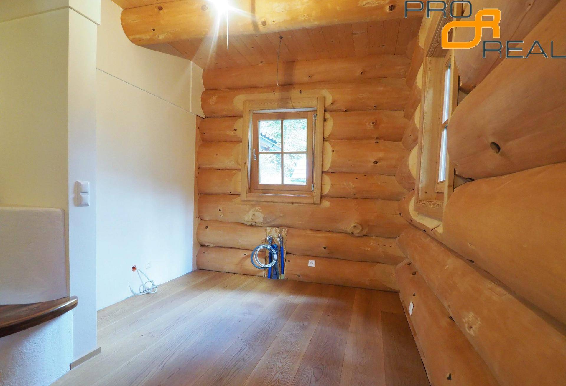 Innenraum mit Holzwänden, Holzboden und Fenster, vorbereitet für weitere Installationen.