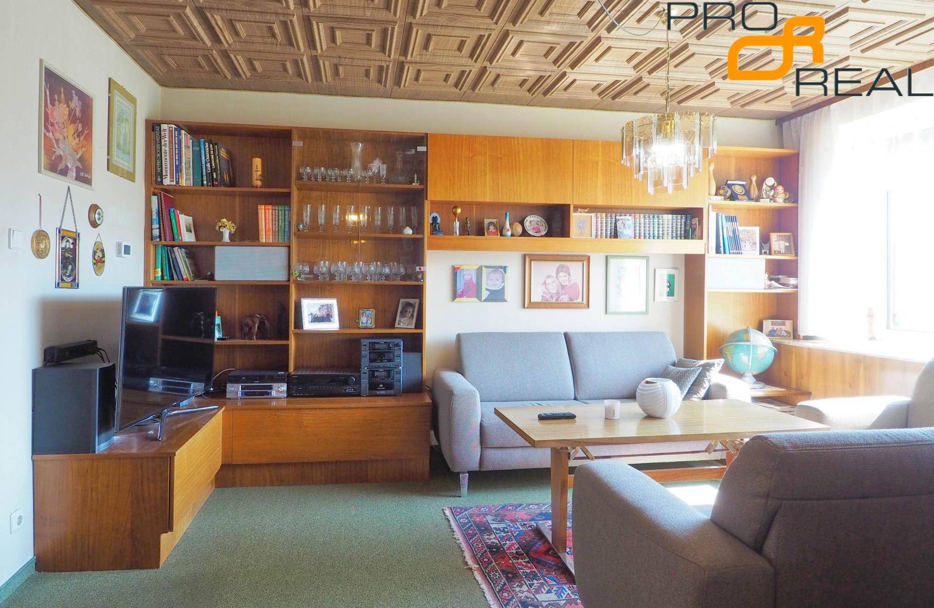 Wohnzimmer mit gemusterter Decke, Einbauregalen und Teppichboden.