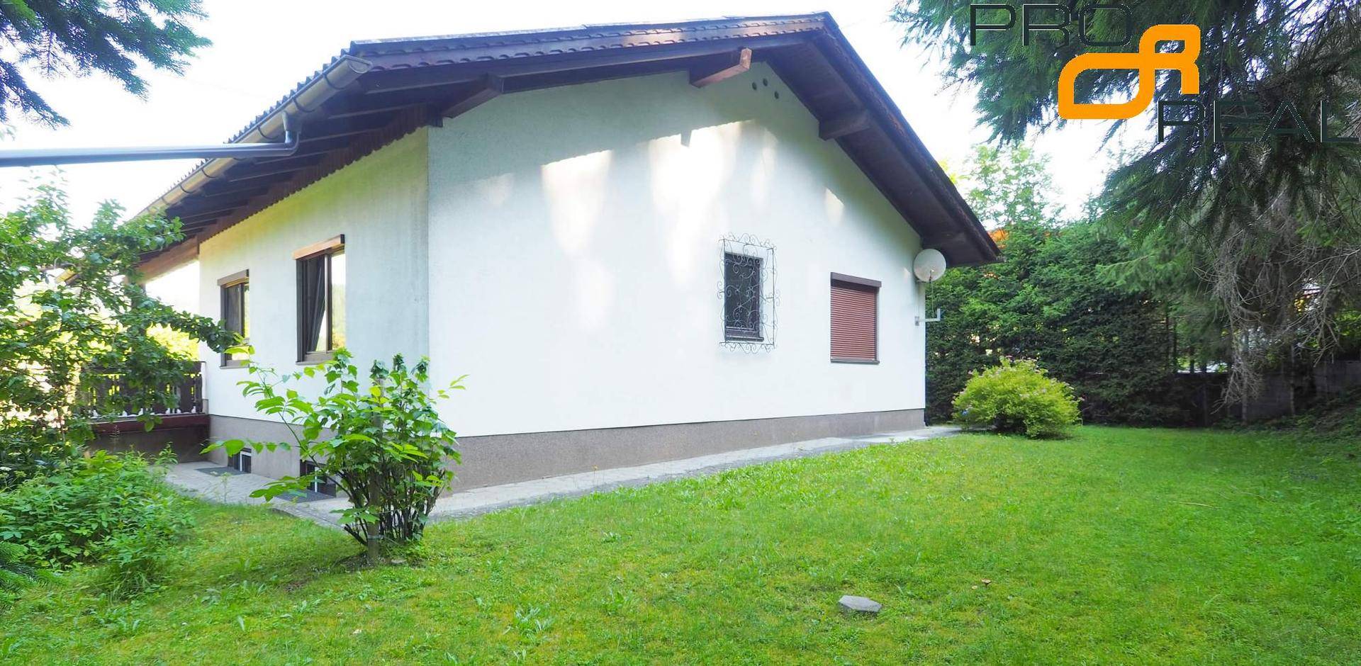 Seitenansicht des Hauses mit gepflegtem Rasen und grüner Bepflanzung.