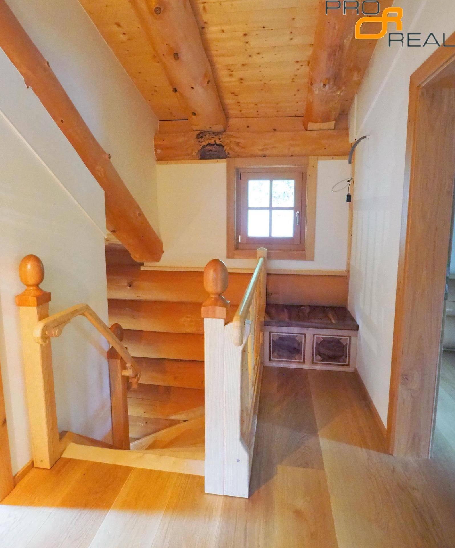 Treppenabsatz mit Holzboden und integrierter Sitzbank, umgeben von Holzelementen.