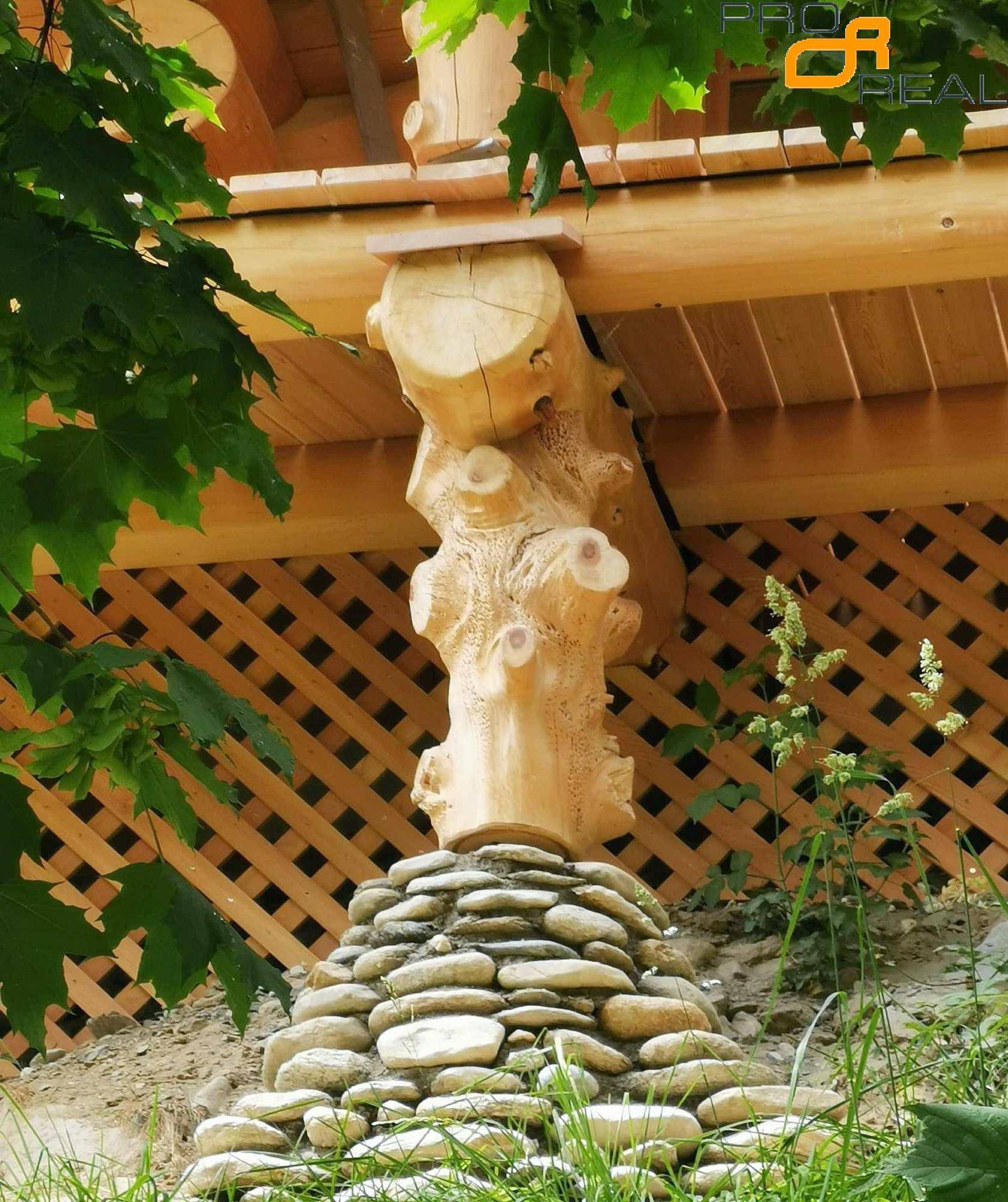 Detail der Holzstütze des Blockhauses, auf einem Steinsockel ruhend.