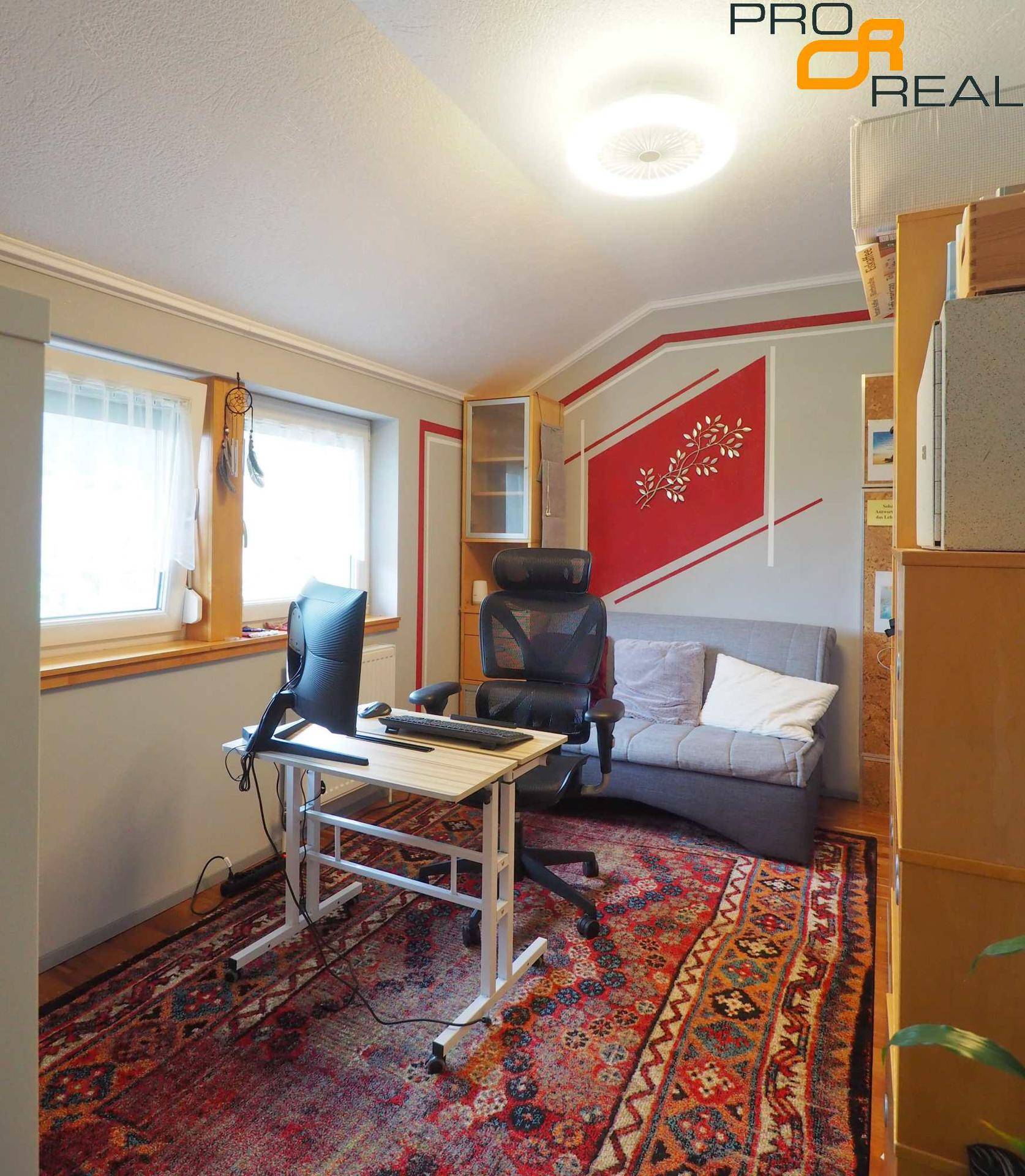 Modernes Heimbüro mit Schreibtisch, Bürostuhl, Sofa und farbenfrohen Dekorationselementen.
