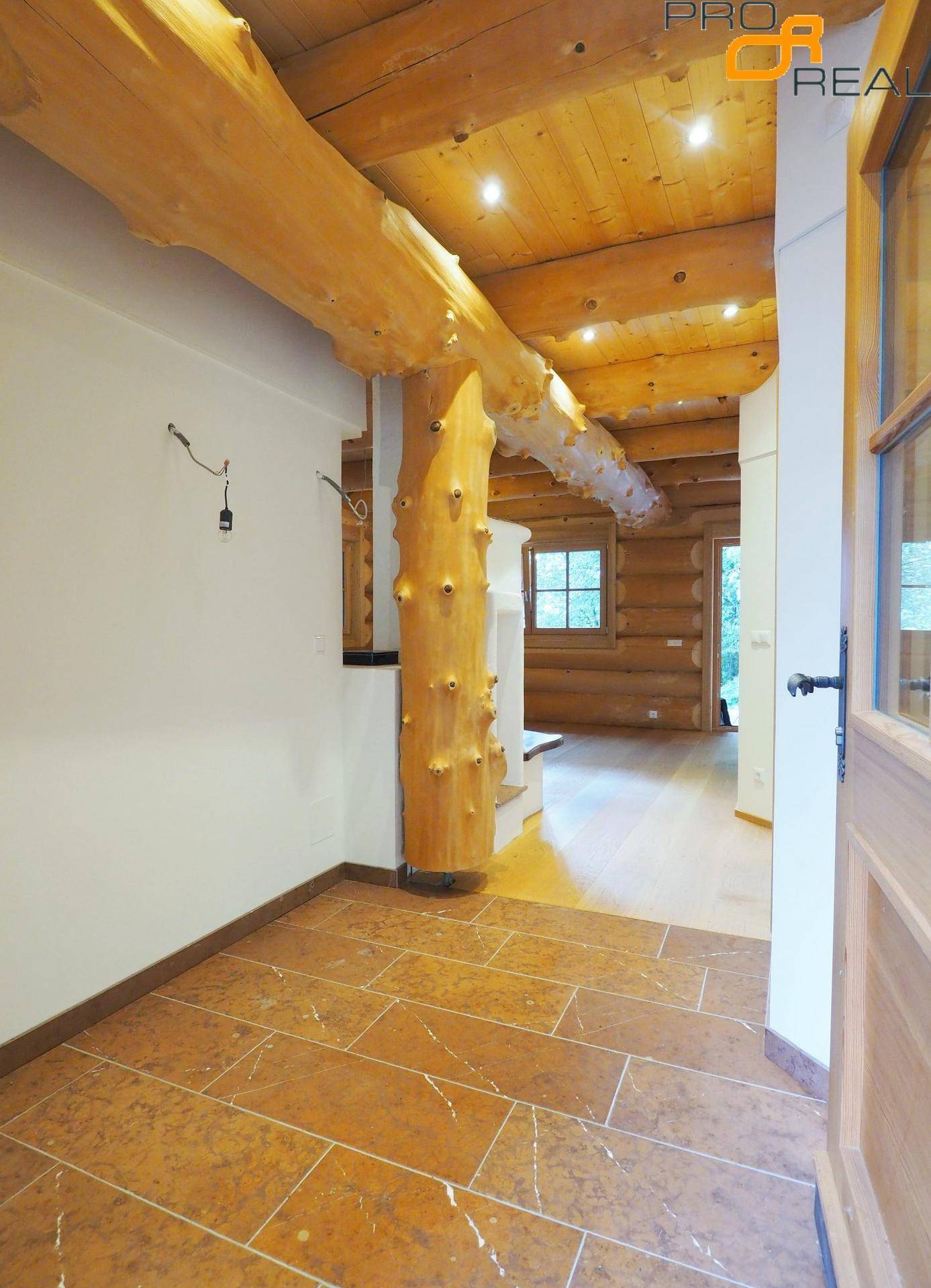 Eingangsbereich mit Fliesenboden und sichtbaren Holzbalken, führt in den Wohnbereich.