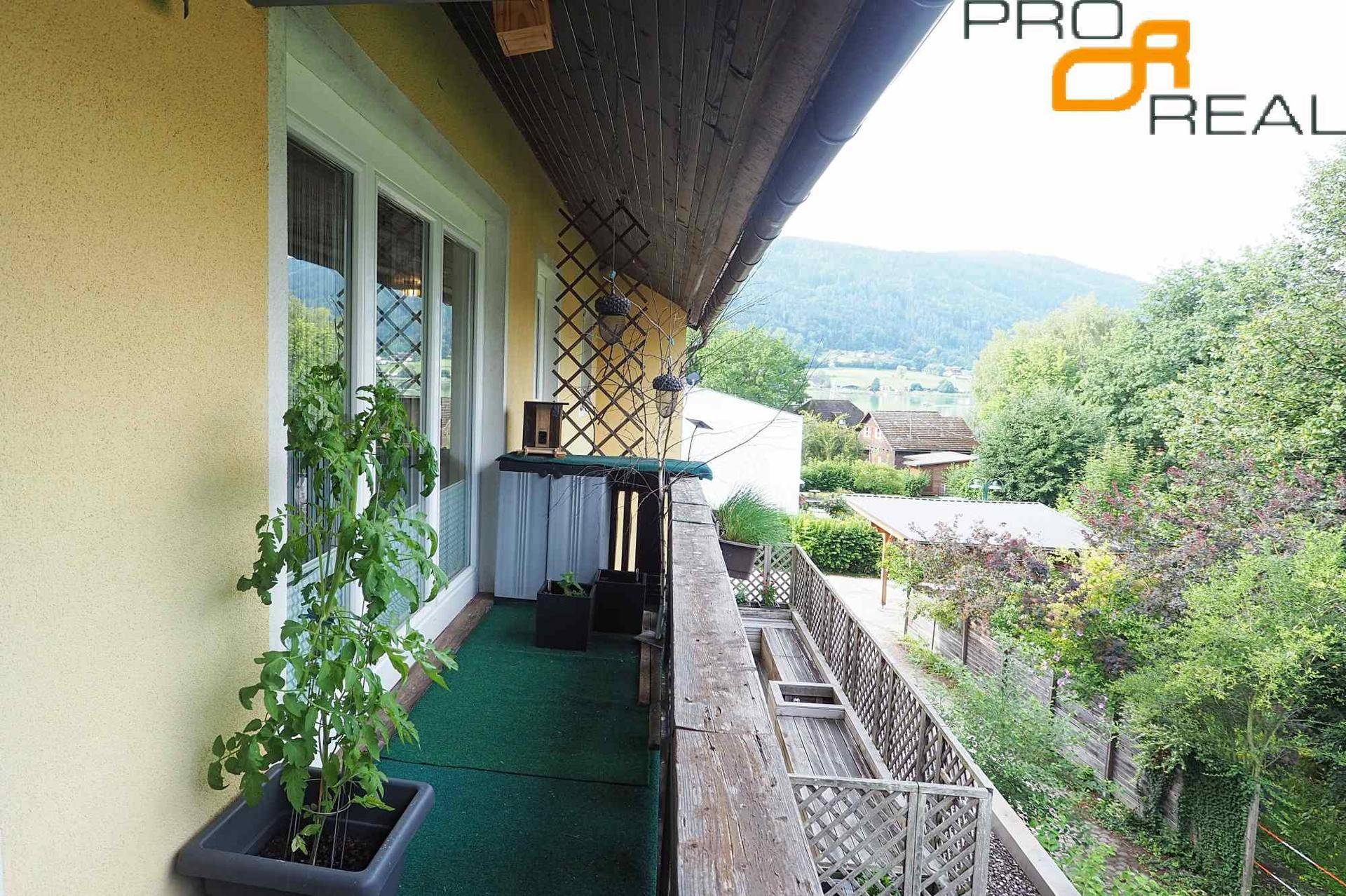 Schmaler Balkon mit Kunstrasen, Holzbalken und weitem Blick auf die umliegende Landschaft.