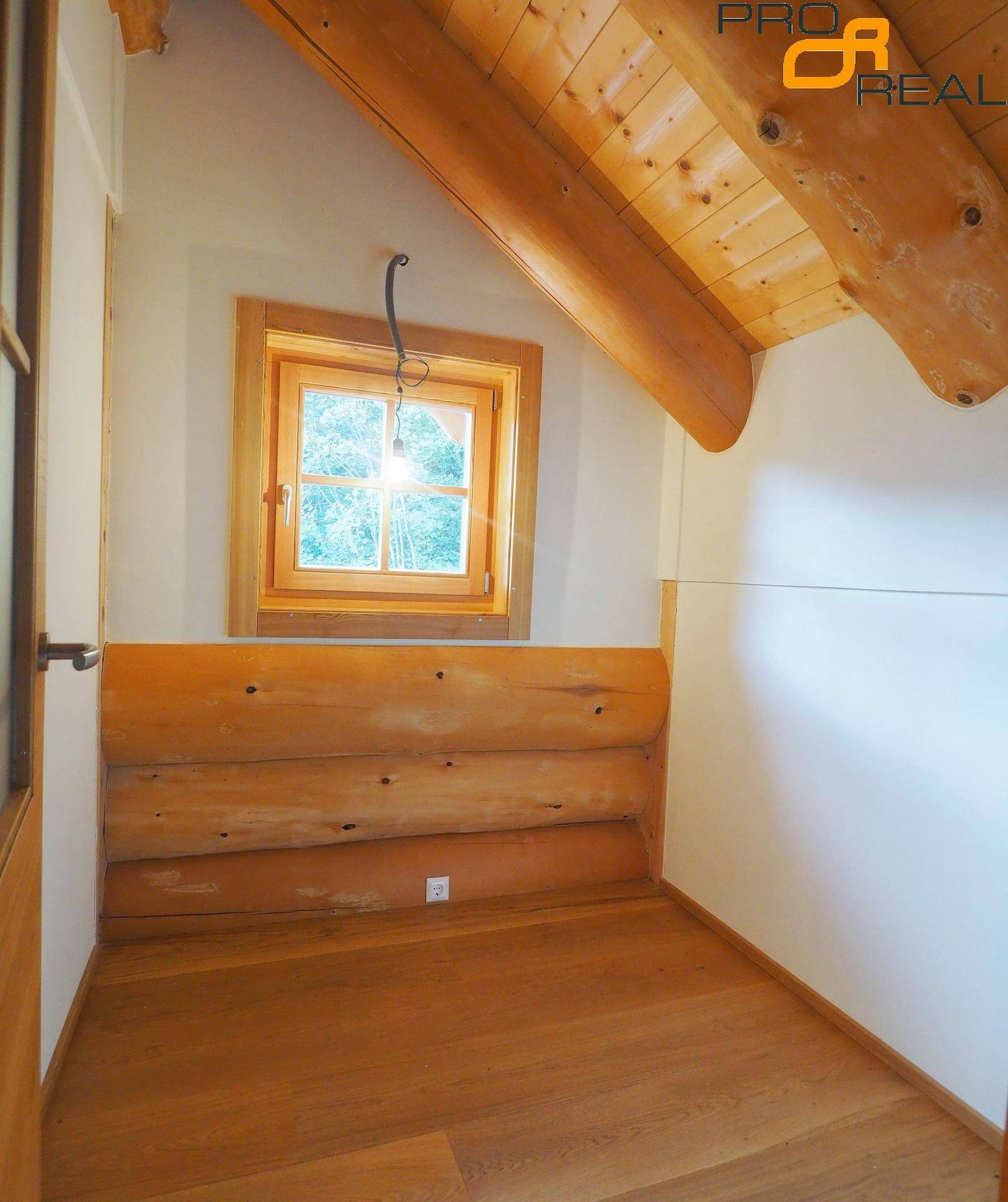 Kleiner Raum mit Holzboden, Holzwänden und Dachschräge, ideal als Kinderzimmer.