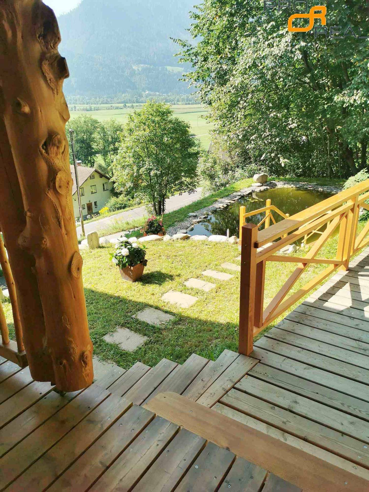 Blick von der Terrasse auf den gepflegten Rasen und den Naturteich.