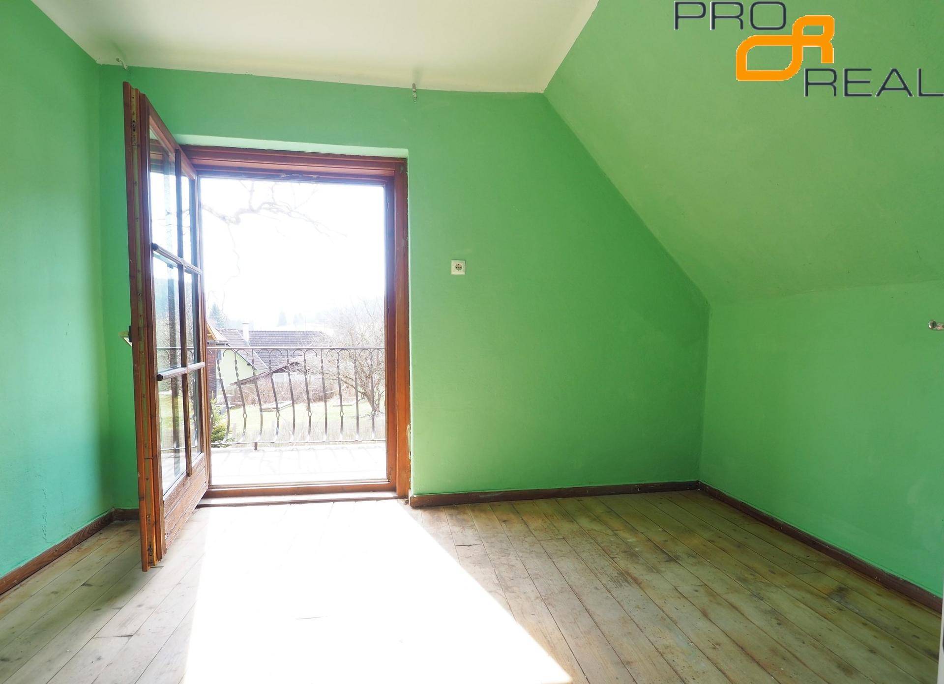 Dachzimmer mit grün gestrichenen Wänden, Holzboden und Zugang zu einem Balkon.