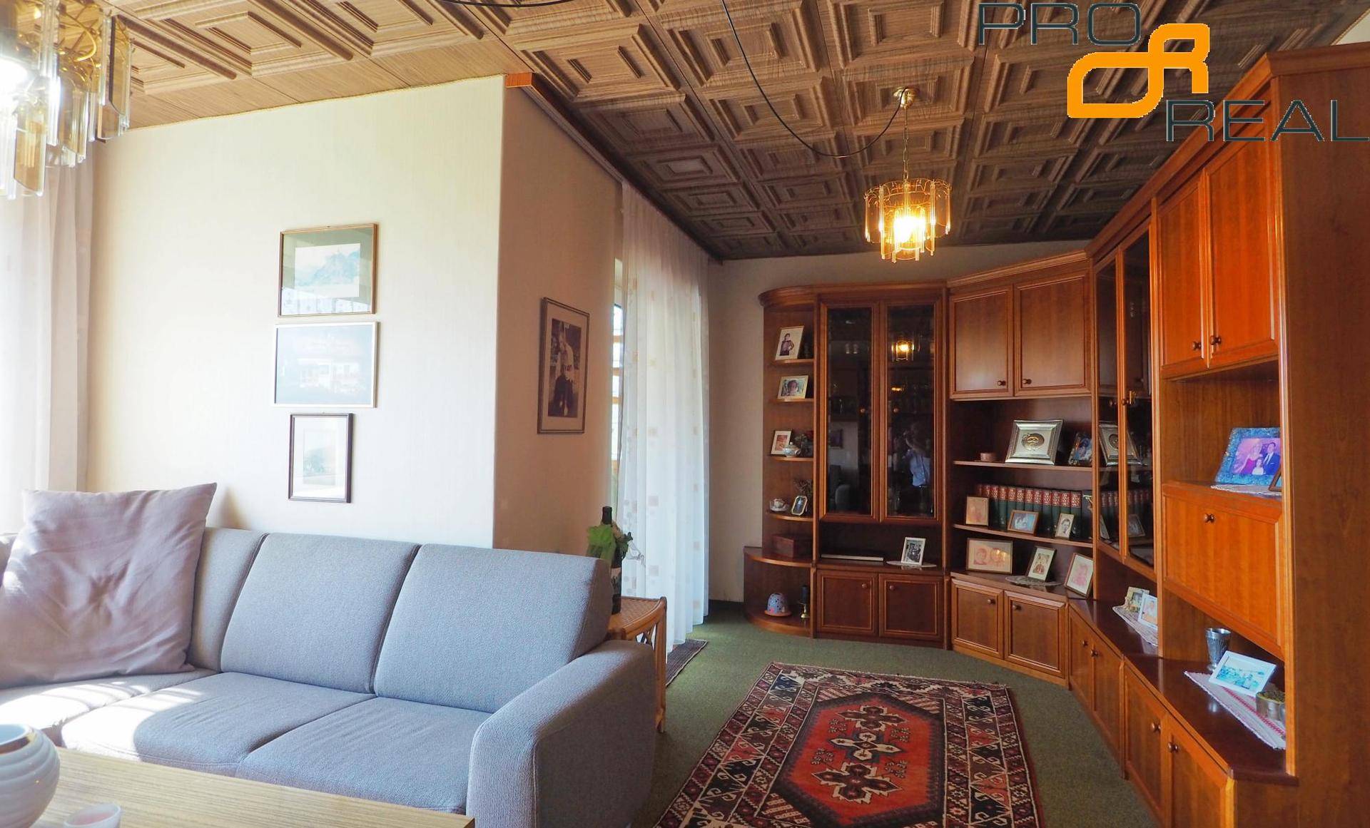 Gemütliches Wohnzimmer mit Sofa, Einbauregalen und gemusterter Decke.