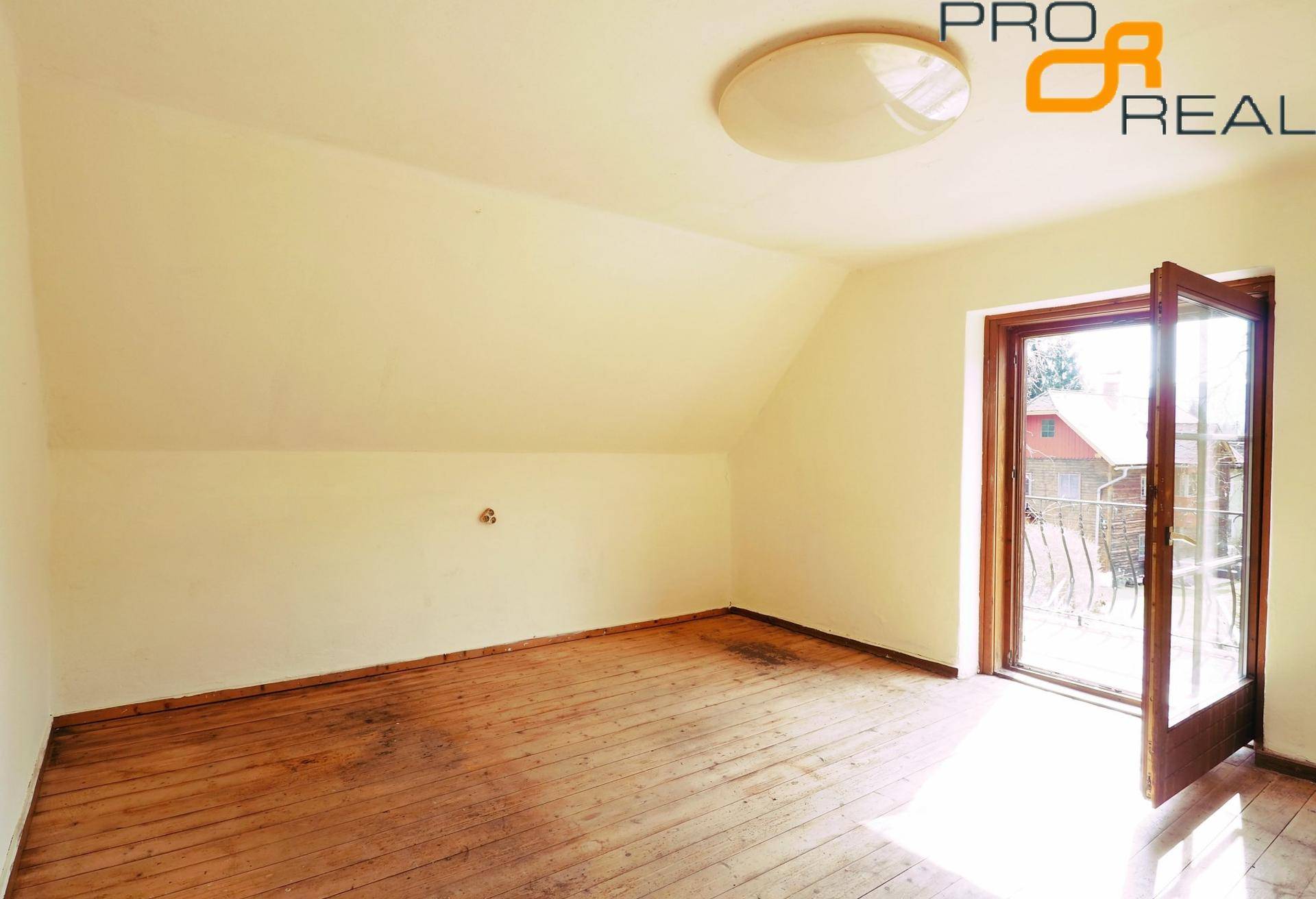 Helles Dachzimmer mit Holzboden und Zugang zu einem Balkon, ideal für Entspannung.