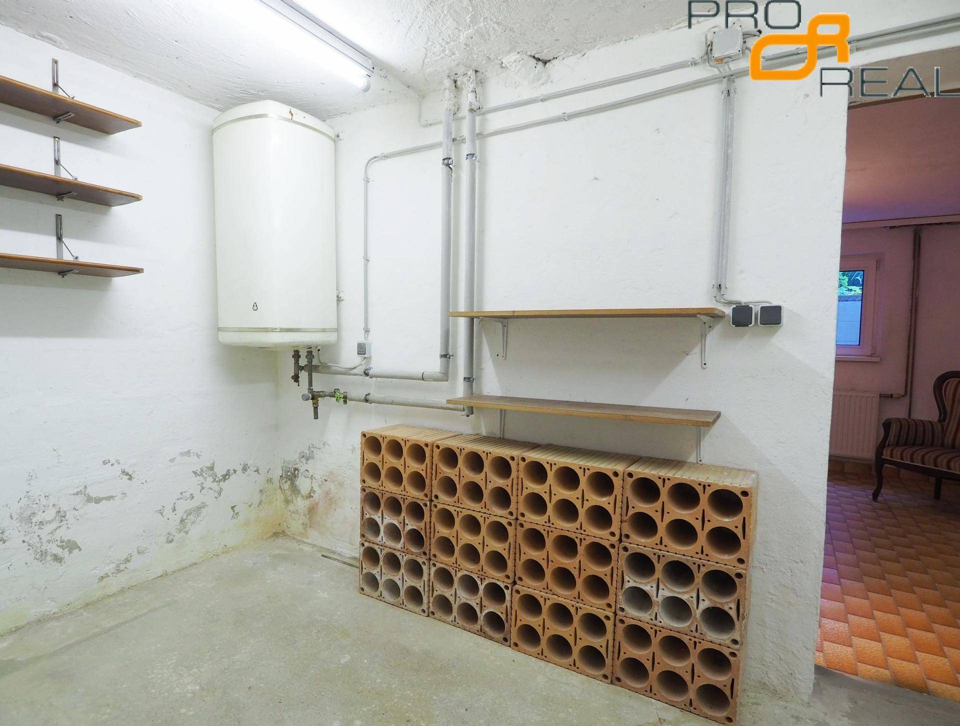 Kellerraum mit Warmwasserbereiter, Regalen und speziellen Racks zur Weinlagerung.