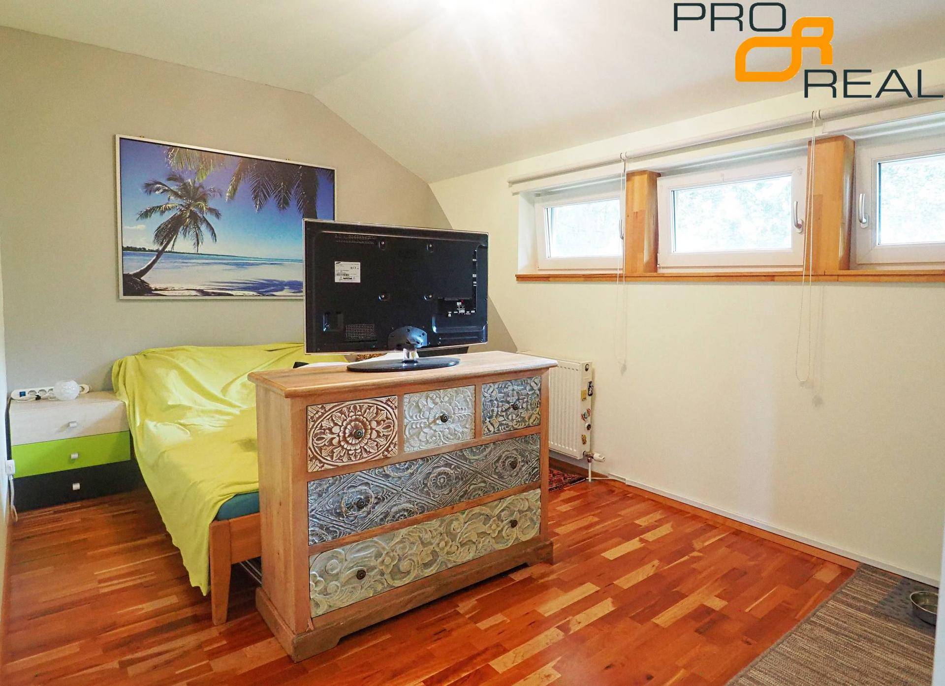 Gemütliches Schlafzimmer mit Dachschräge, Holzboden und einem dekorativen Sideboard.