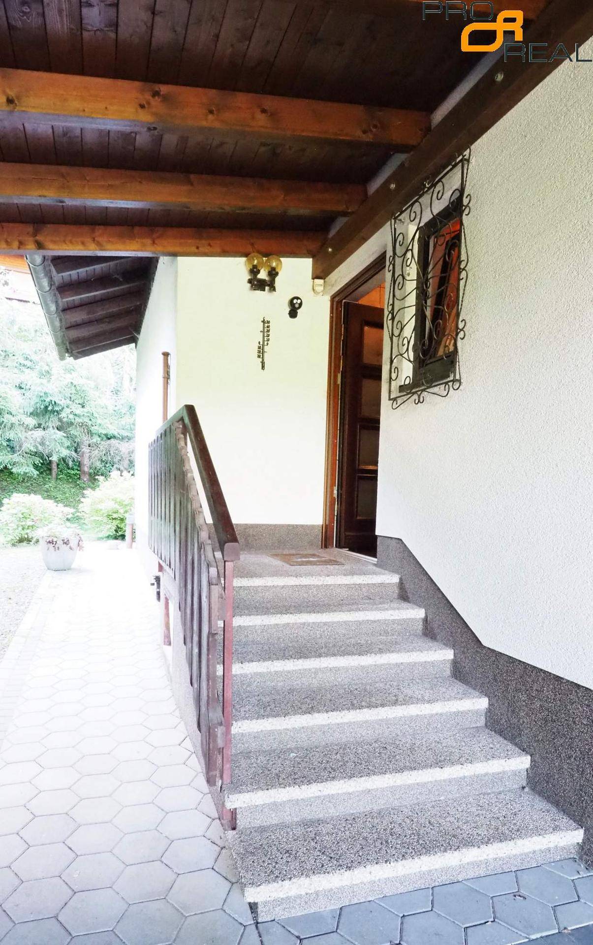 Eingangsbereich mit Steintreppe und überdachtem Zugang, geschützt durch ein Holzdach.