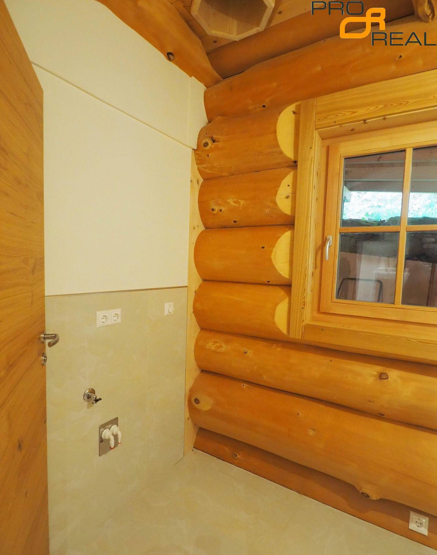 Kleiner Raum mit Holzwänden und Anschlussmöglichkeiten für Waschmaschine.