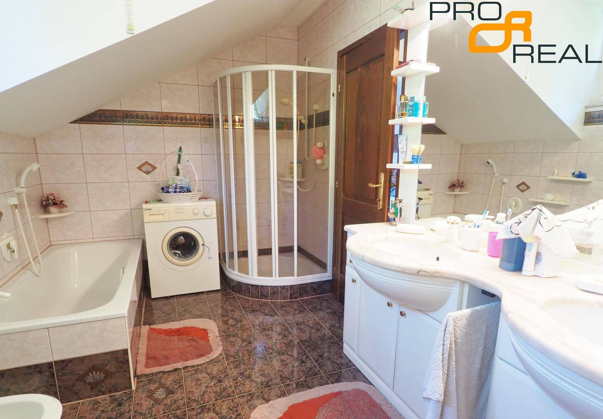 Badezimmer mit Dusche, Badewanne, Waschmaschine und Dachschräge.