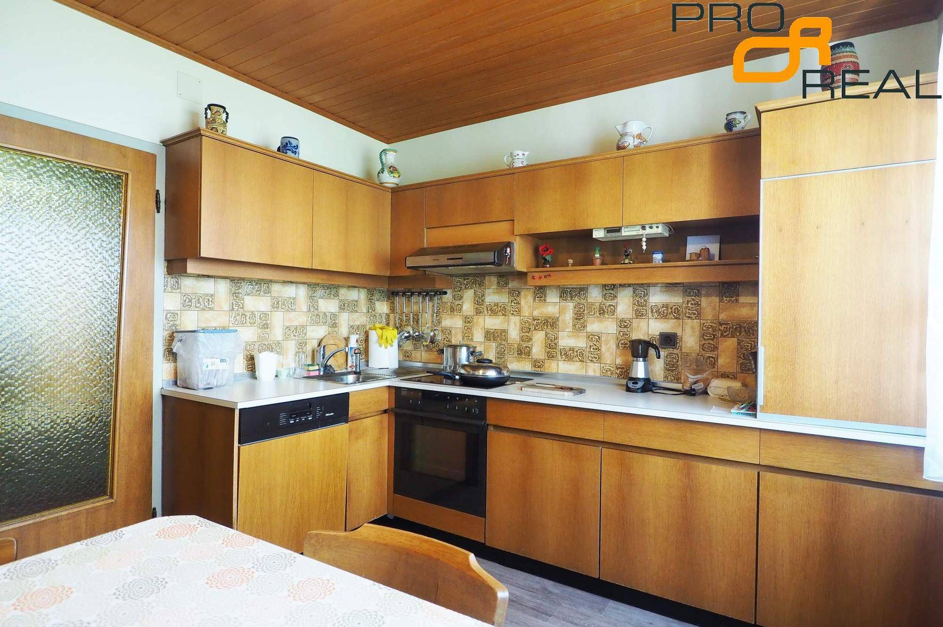 Funktionale Küche mit Holzschränken, Spülmaschine und traditionellem Fliesenspiegel.