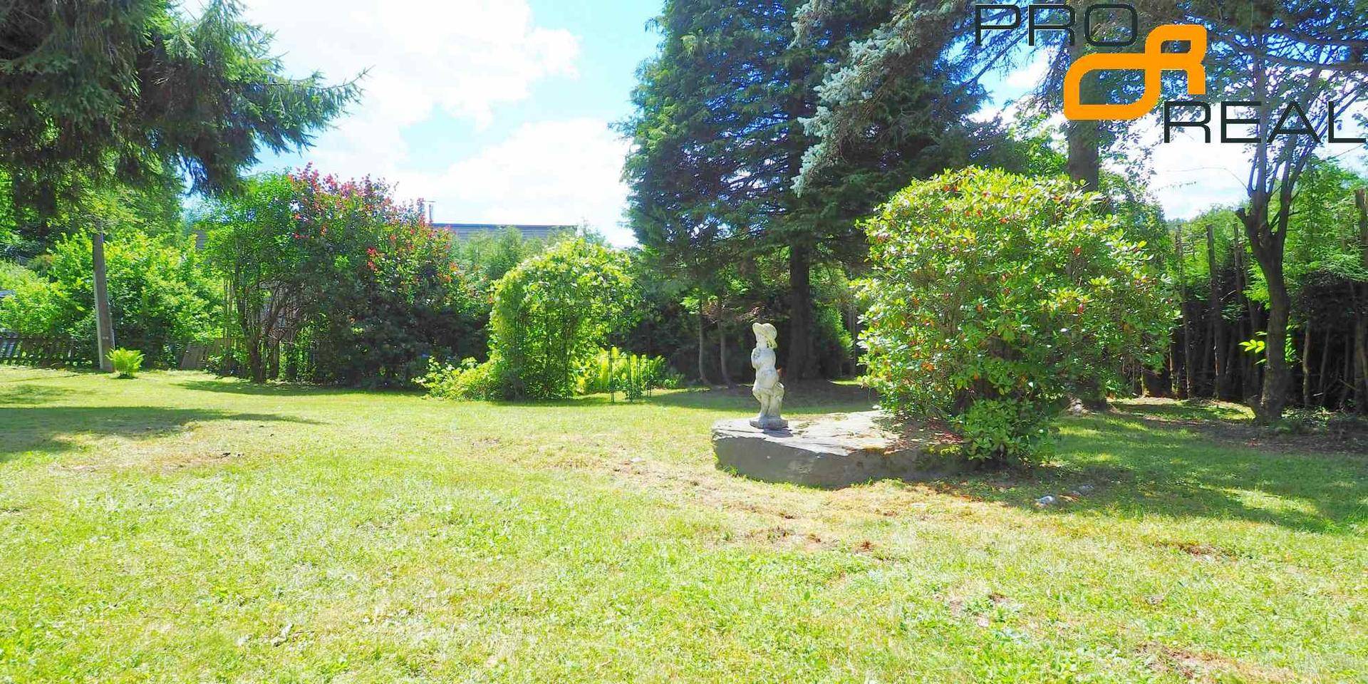 Großer, gepflegter Garten mit Rasenfläche und dekorativer Statue unter blauem Himmel.