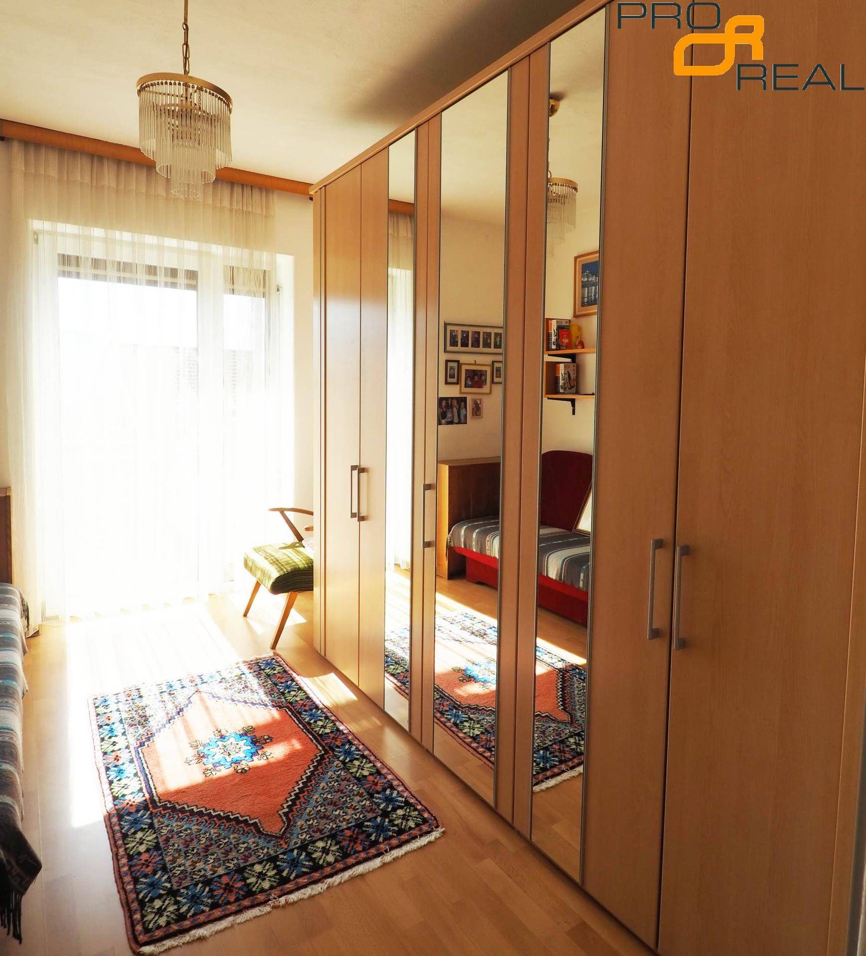 Helles Schlafzimmer mit Spiegelschränken, Holzboden und Teppich.