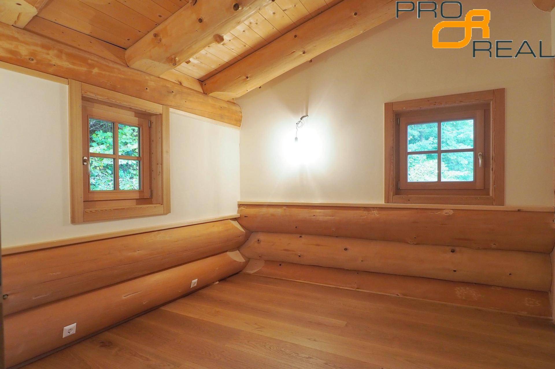 Gemütliches Schlafzimmer mit Holzboden und Holzwänden, durchflutet von Tageslicht.
