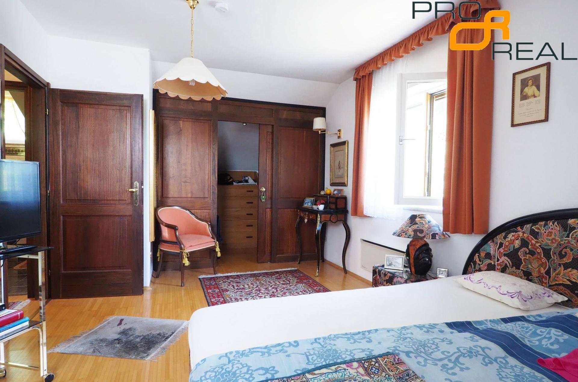 Schlafzimmer mit Holzboden, Einbauschränken und Fenster mit Vorhängen.