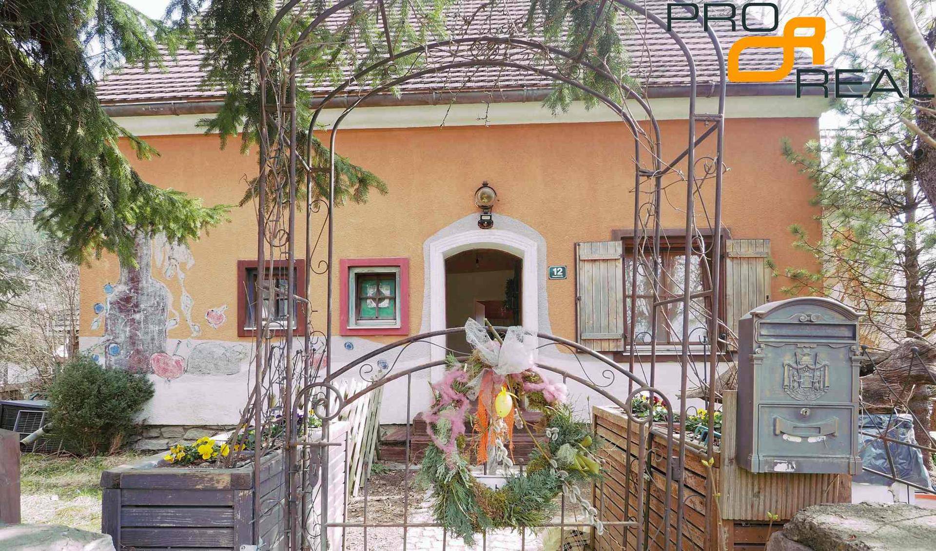 Traditionelles Haus mit ockerfarbener Fassade, Holztüren und einem dekorativen Eingangsbogen.