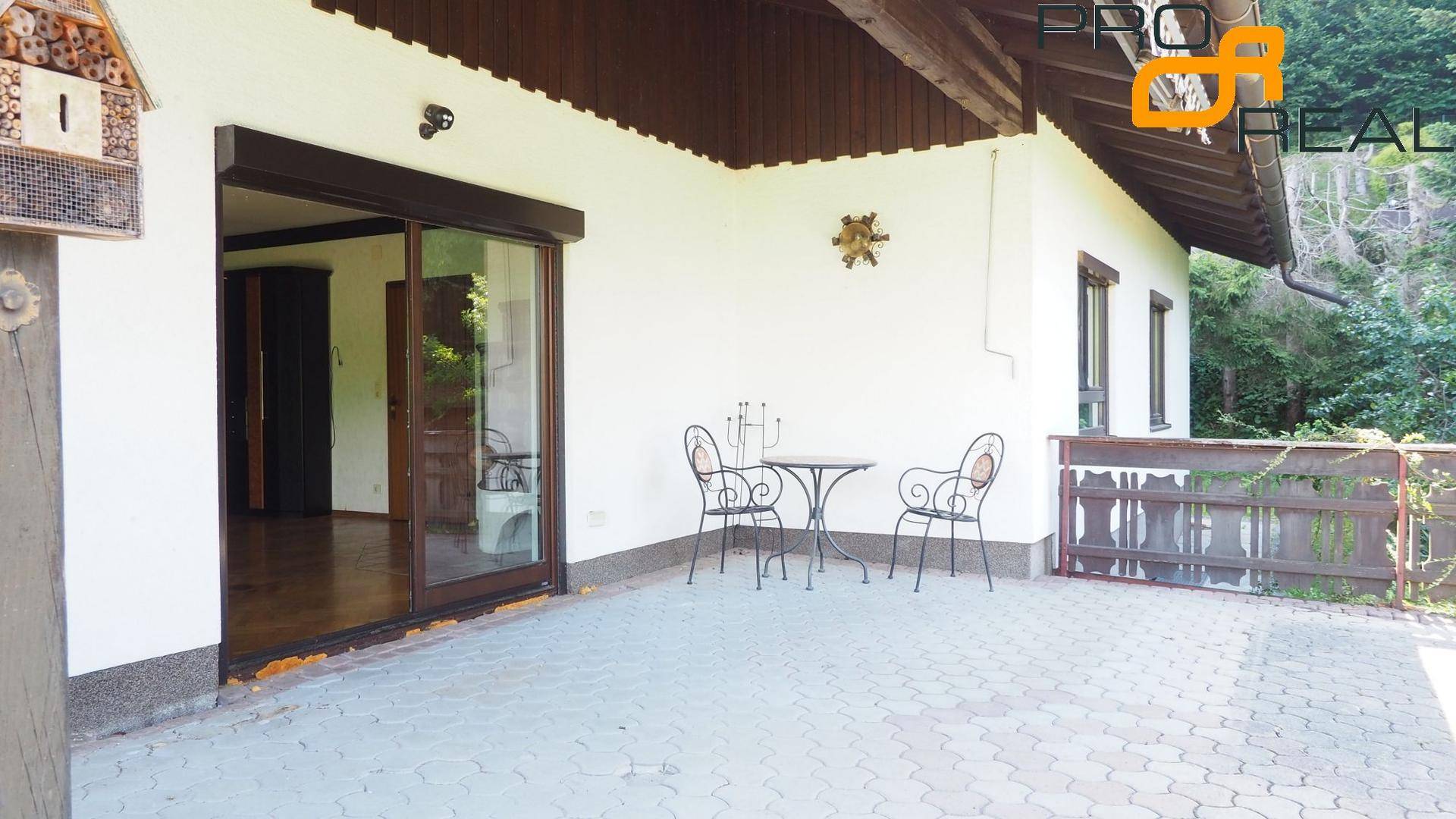 Terrasse mit Zugang zum Innenbereich durch eine große Schiebetür und schmiedeeisernen Möbeln.