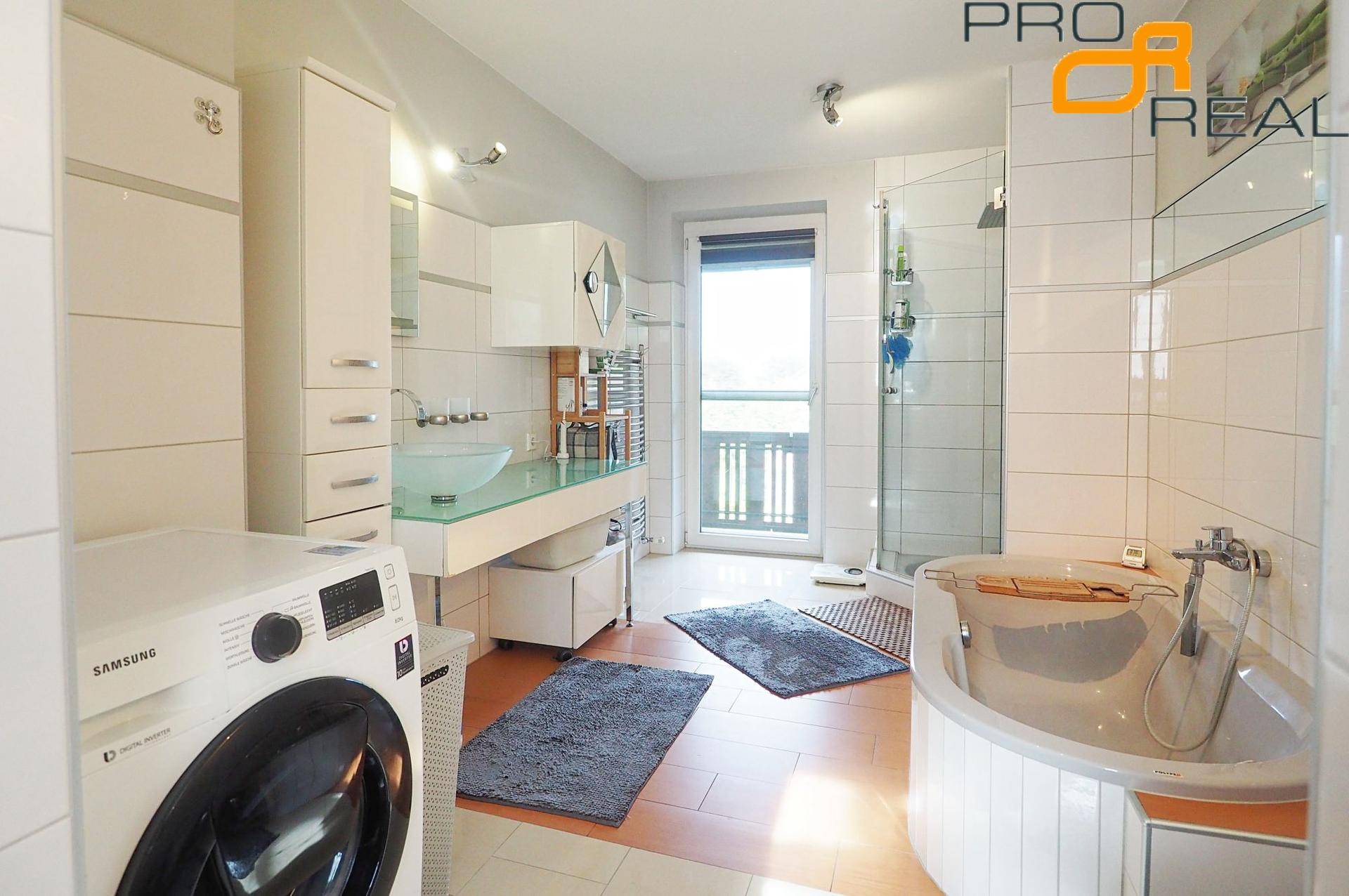 Geräumiges Badezimmer mit Waschmaschine, Doppelwaschbecken, Dusche und Eckbadewanne.