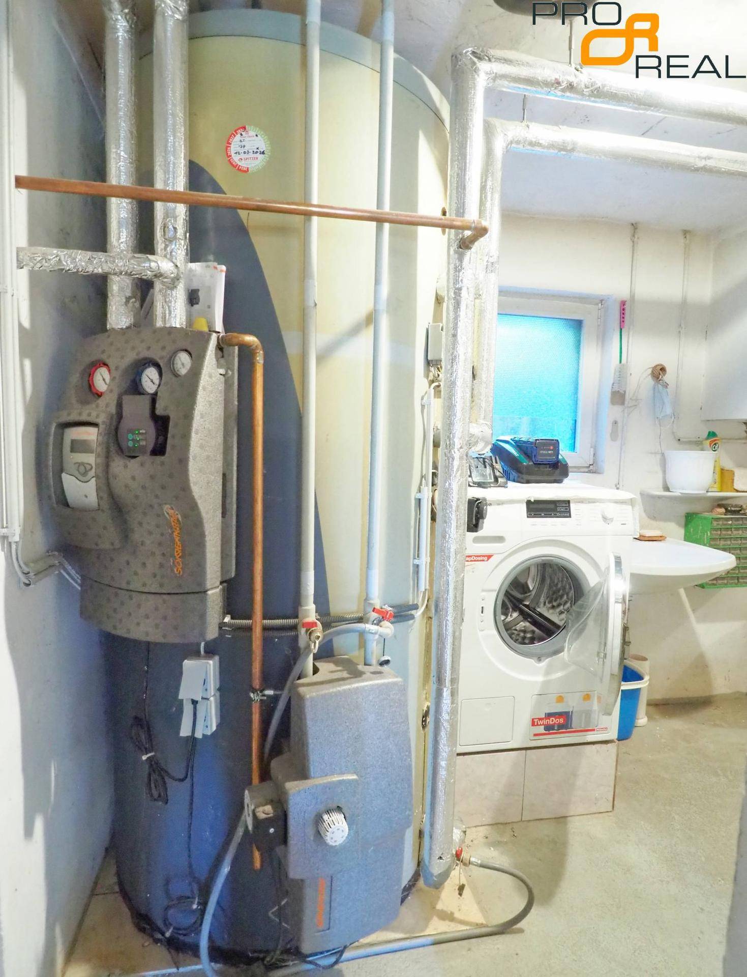 Heizungsraum im Keller mit Boiler, Rohren und Waschmaschine.