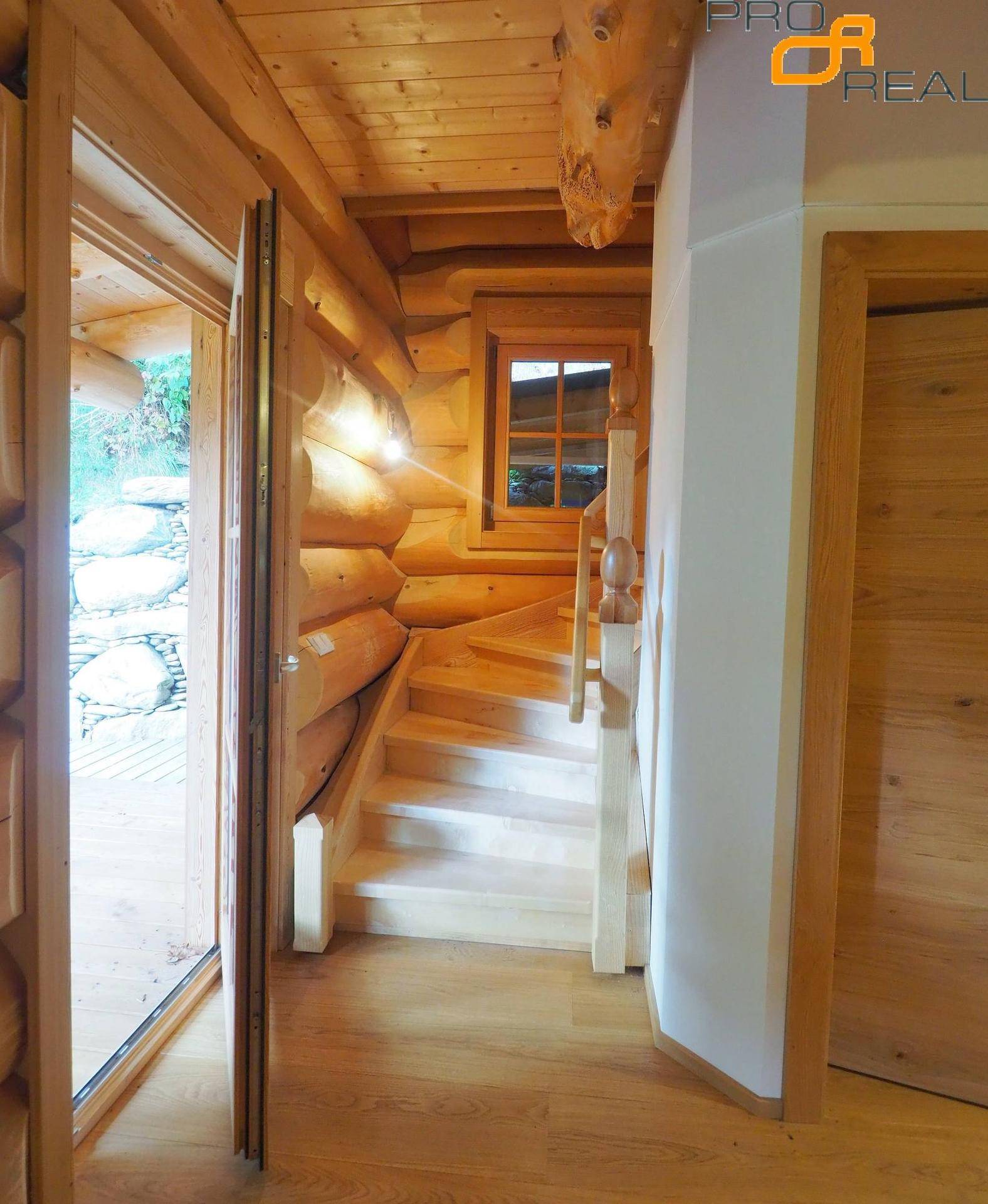 Holztreppe führt in die obere Etage, umgeben von rustikalen Holzwänden.
