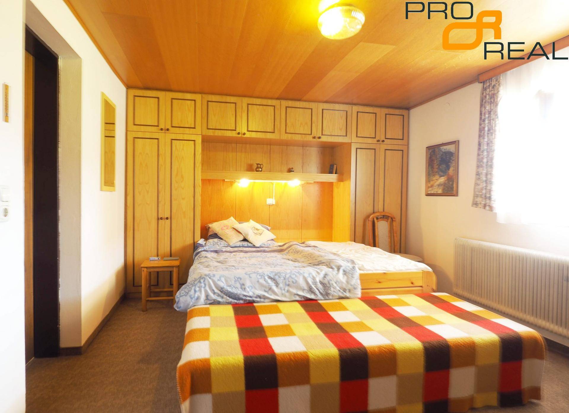Schlafzimmer mit Holzbett, Einbauschränken und Holzdecke.
