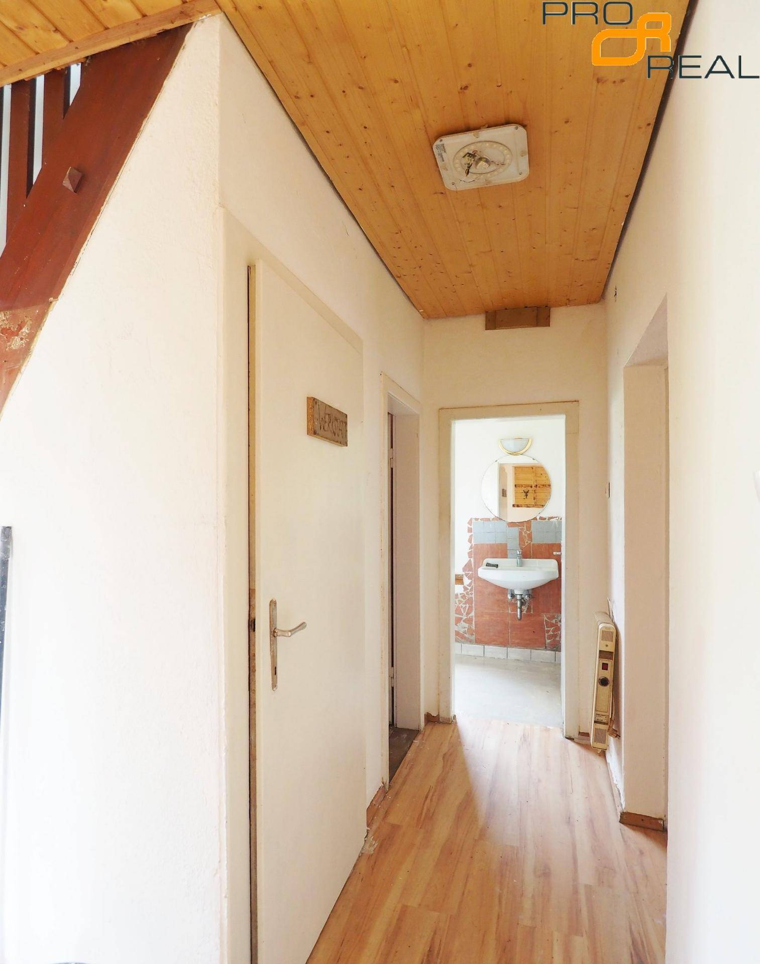 Heller Flur mit Holzdecke und Holzboden, der zu weiteren Räumen führt.
