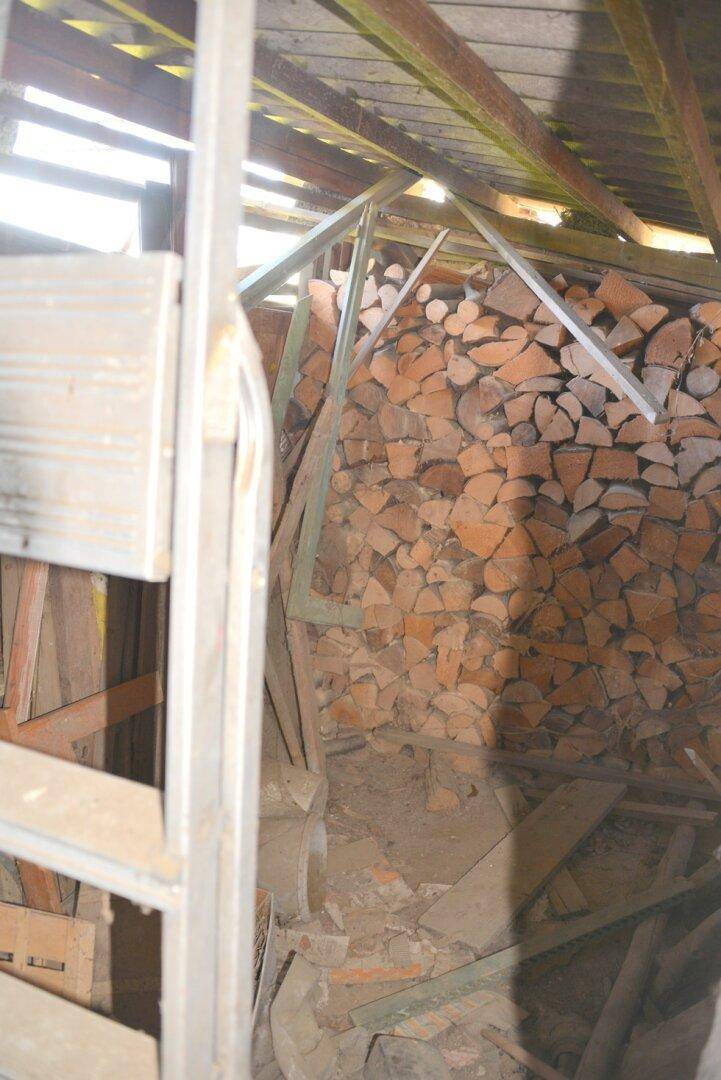 Dachbodenbereich mit gestapeltem Brennholz und sichtbarer Holzkonstruktion, der als Lagerraum dient.