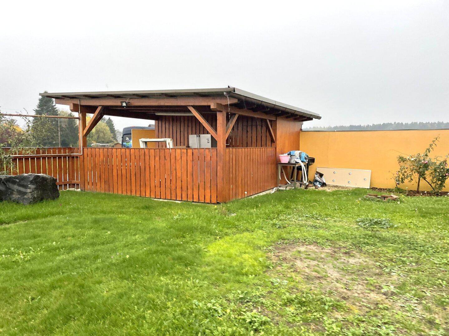 Gartenbereich mit Rasenfläche und einer überdachten Holzpergola für gemütliche Stunden im Freien.