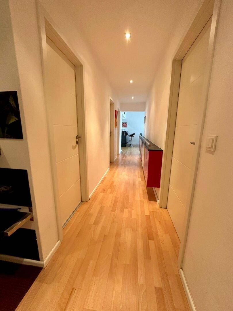 Langer, heller Flur mit Holzparkettboden und Türen zu verschiedenen Räumen.