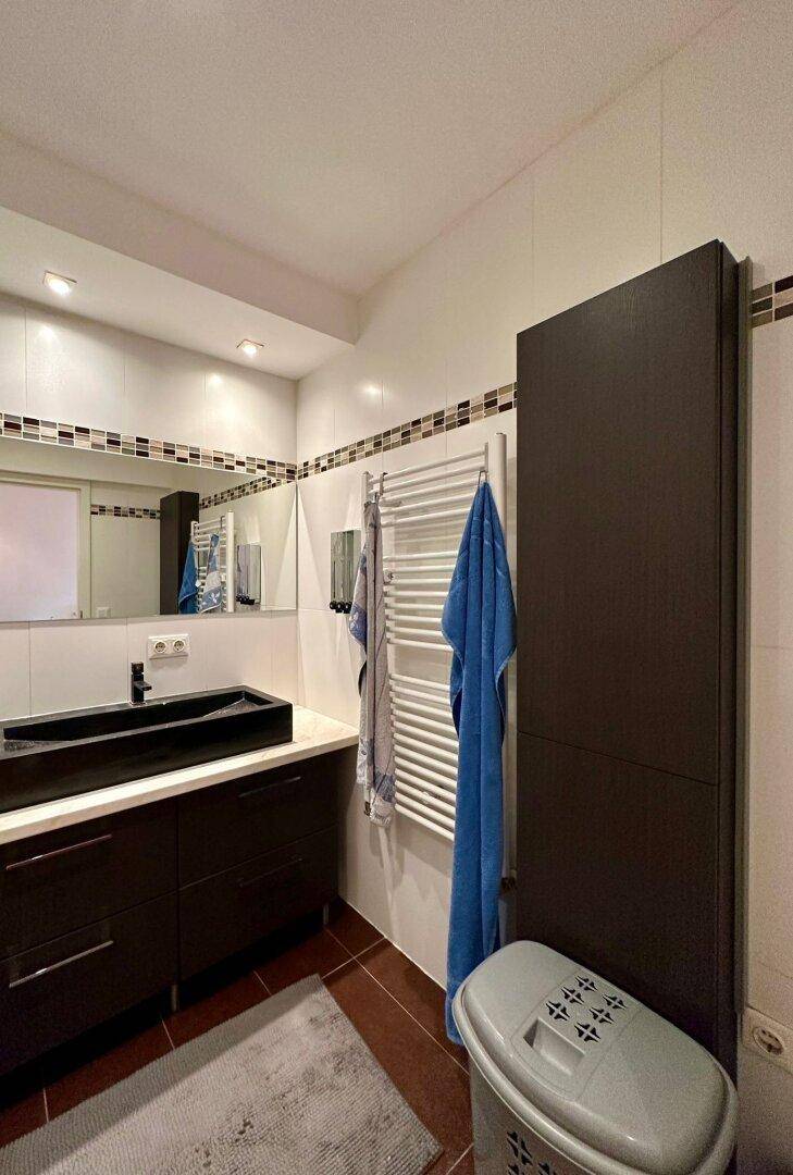 Modernes Badezimmer mit dunklem Waschtisch, weißem Fliesenspiegel und beheiztem Handtuchhalter.